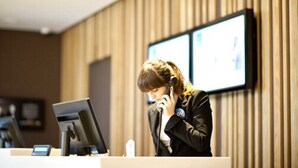 A reception desk with a computer monitor, a phone, and a framed picture on the wall. - Novotel Lodz Centrum (Lodz)