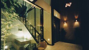 A modern interior with a glass staircase, a seating area, and a spa-like setting with a hot tub. - Hotel Allamanda (Nara)