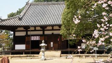 Ein traditionelles japanisches Gebäude mit einem Ziegeldach und einer Steinhlaterne davor.
