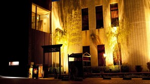 A building with a brick facade, large windows, and a well-lit entrance area with outdoor seating. - Hotel Allamanda (Nara)
