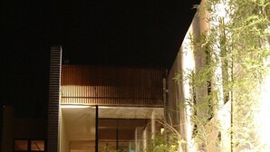 A modern building with a vertical wooden slat facade, a narrow water feature, and potted plants. - Hotel Allamanda (Nara)