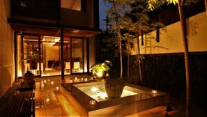 A modern building with a glass entrance, a water feature, and a bench.