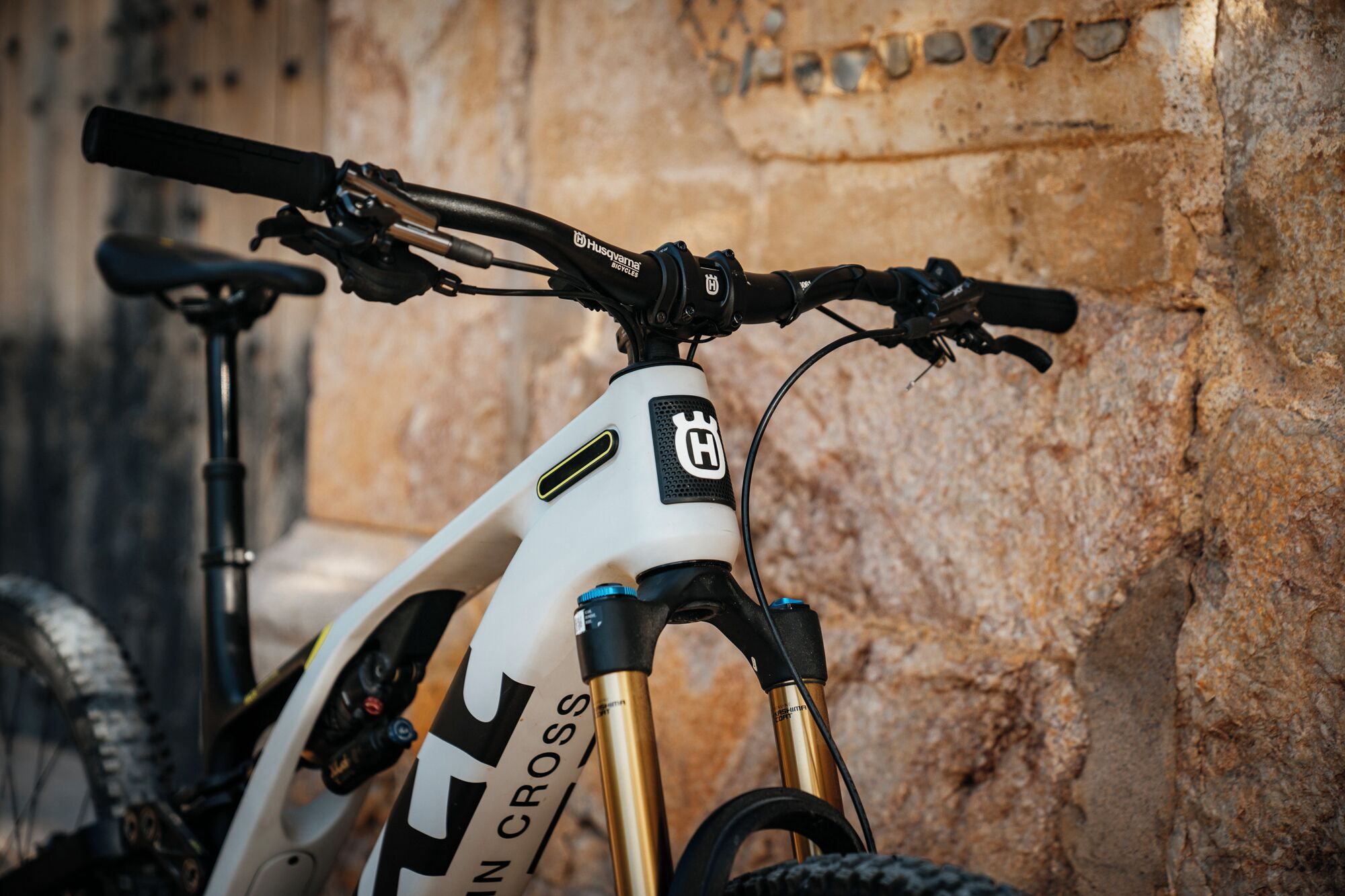 A close-up of a mountain bike with a white frame and gold accents, branded with 'Husqvarna Bicycles'.