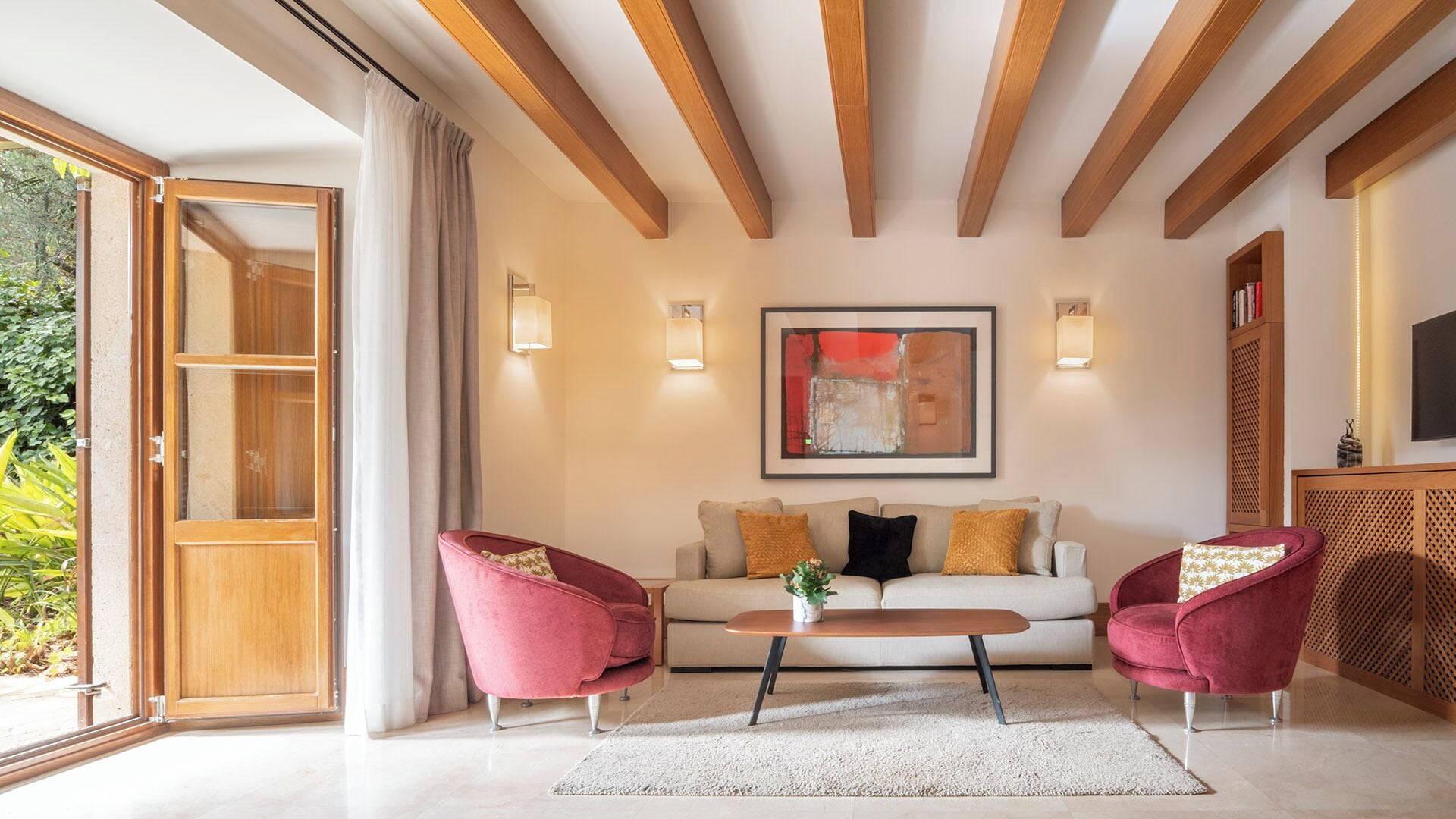 Een moderne woonkamer met een bank, twee fauteuils, een salontafel en een groot raam.