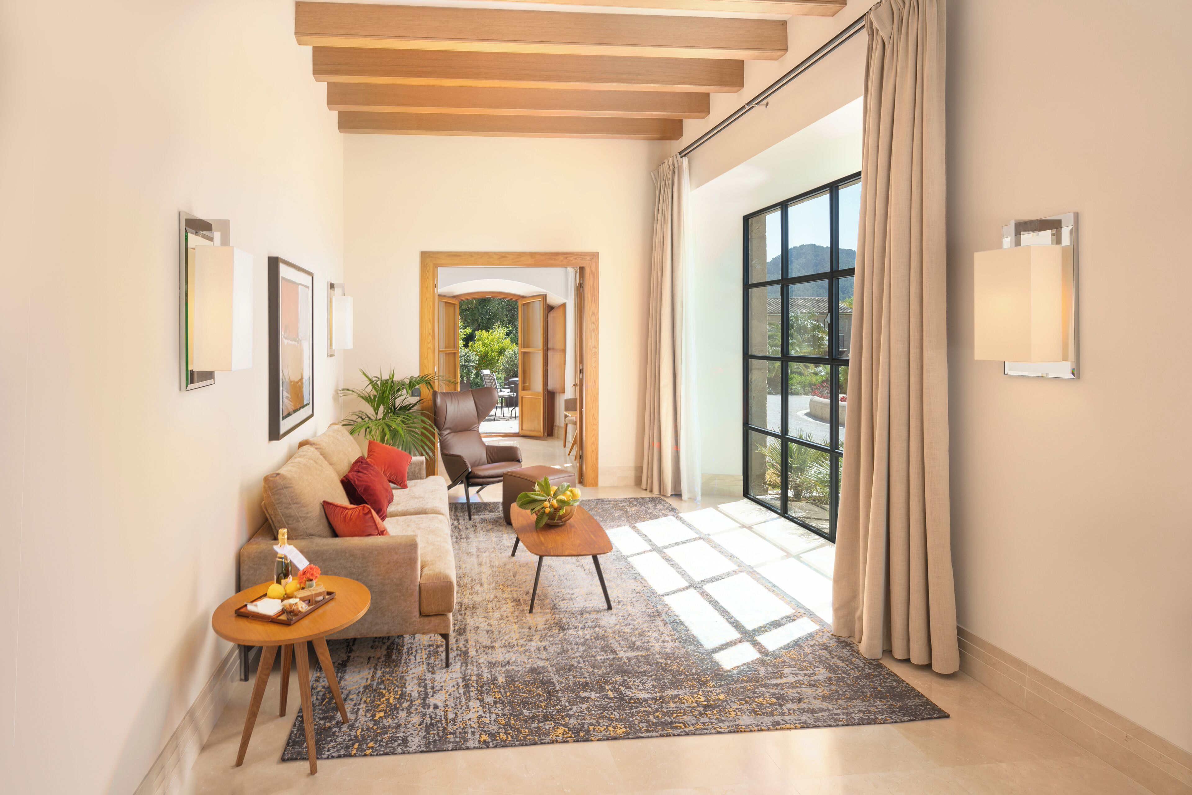 A modern living room with a sofa, coffee table, and a view through a large window.