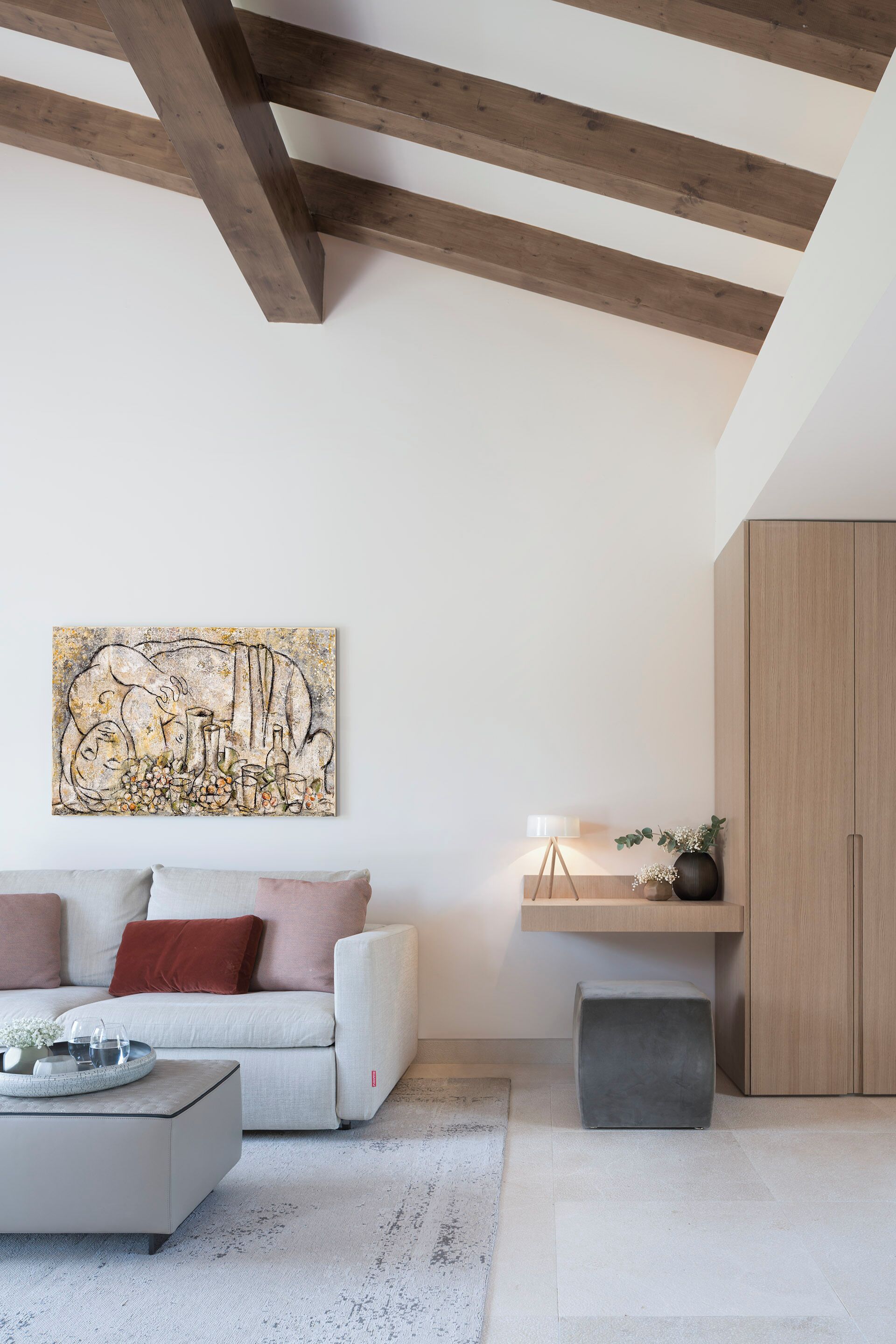 A modern living room with a white sofa, a coffee table, a wooden cabinet, and a painting on the wall.