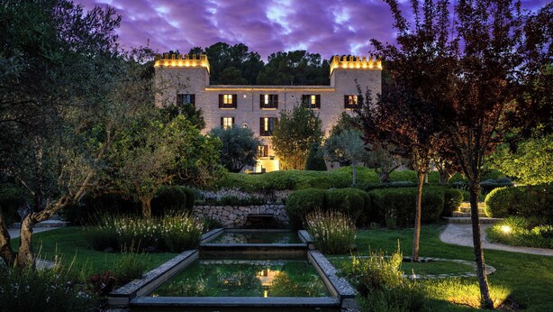 A castle-like building with a moat and well-manicured garden.