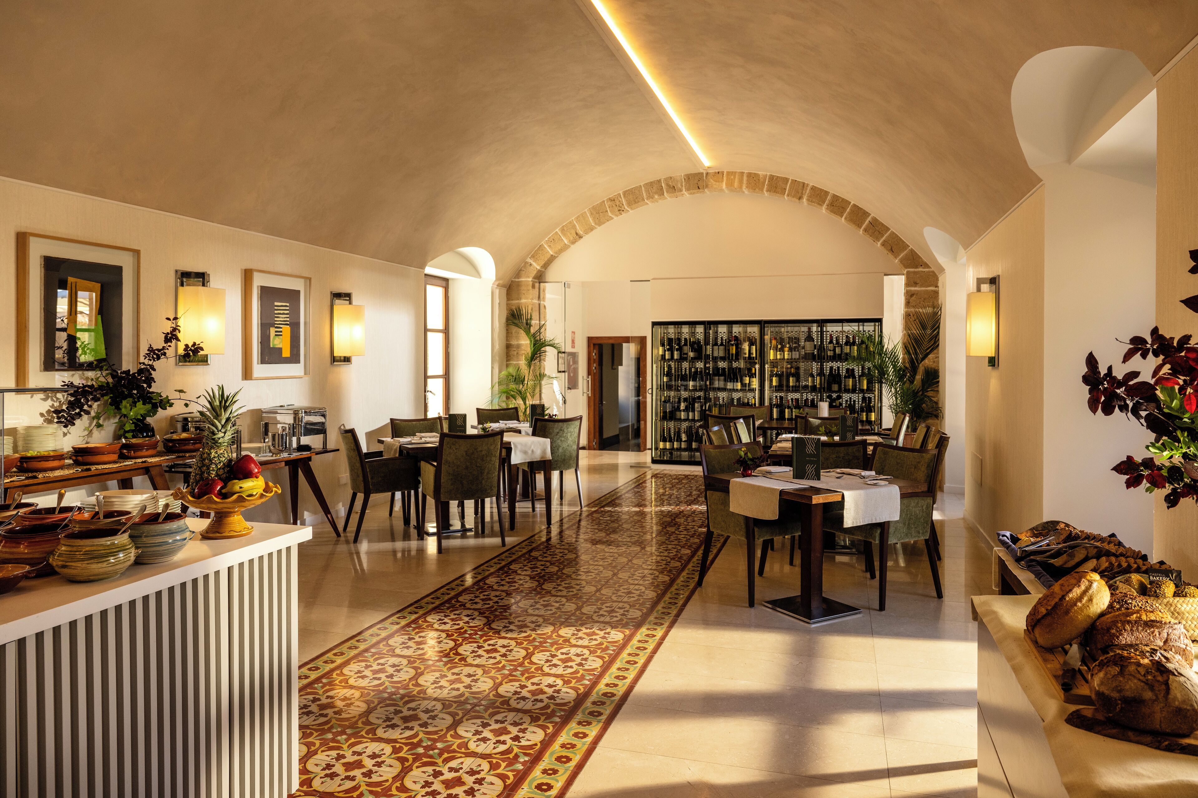 Un amplio vestíbulo de hotel con zona de comedor central, un bar y una cava de vinos.