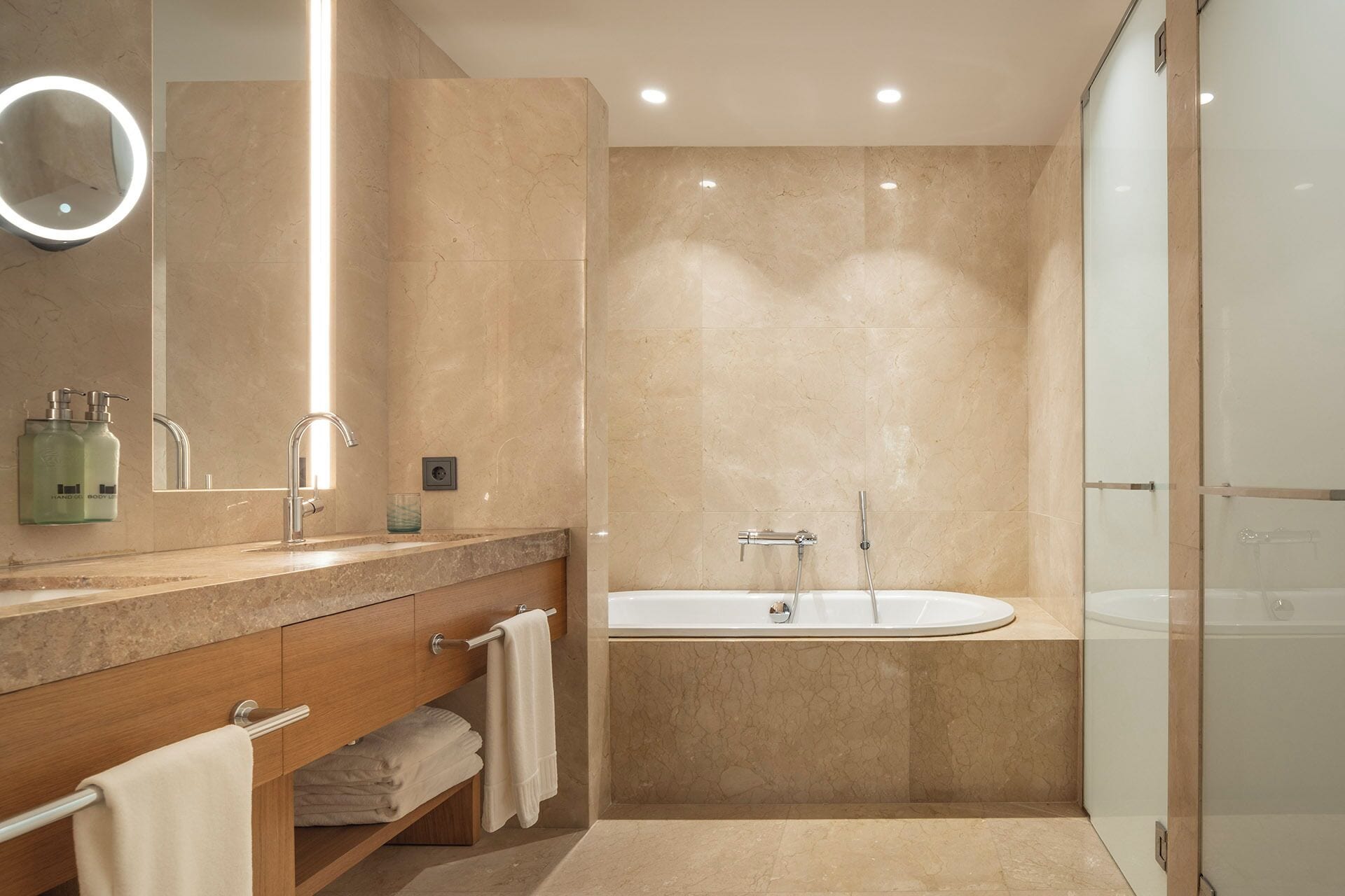 A modern bathroom with a vanity, a large mirror, a bathtub, and a glass shower enclosure.