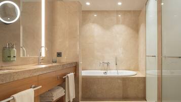 A modern bathroom with a vanity, a large mirror, a bathtub, and a glass shower enclosure.