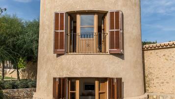 Un edificio cilíndrico con balcón, una puerta y una pequeña mesa con sillas.