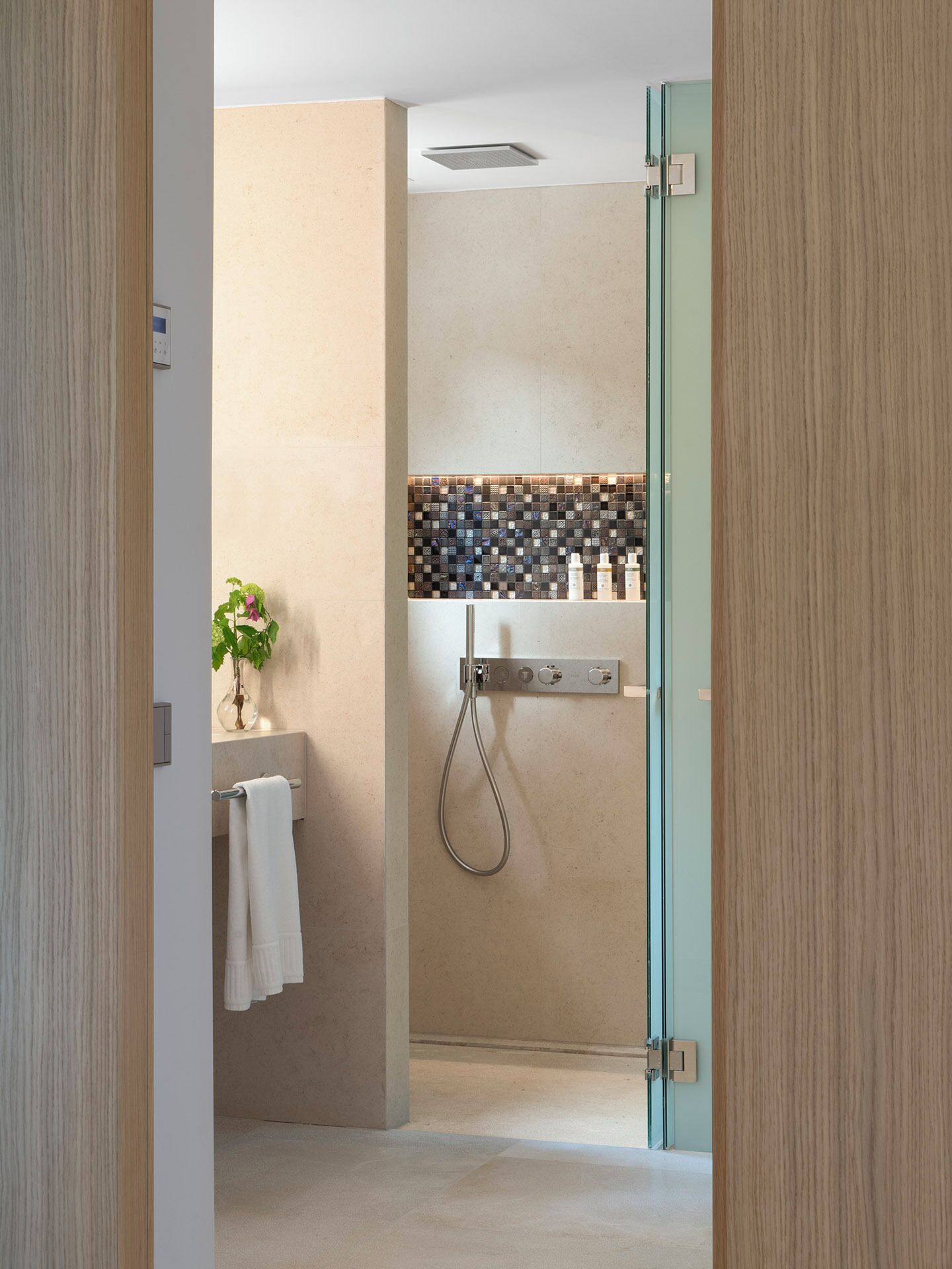 Un baño moderno con ducha, puerta de cristal y salpicadero de azulejos.