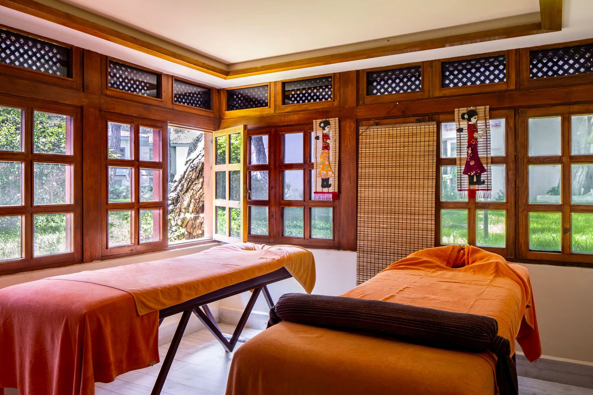 A room with two beds, large windows, and a traditional wooden ceiling design.