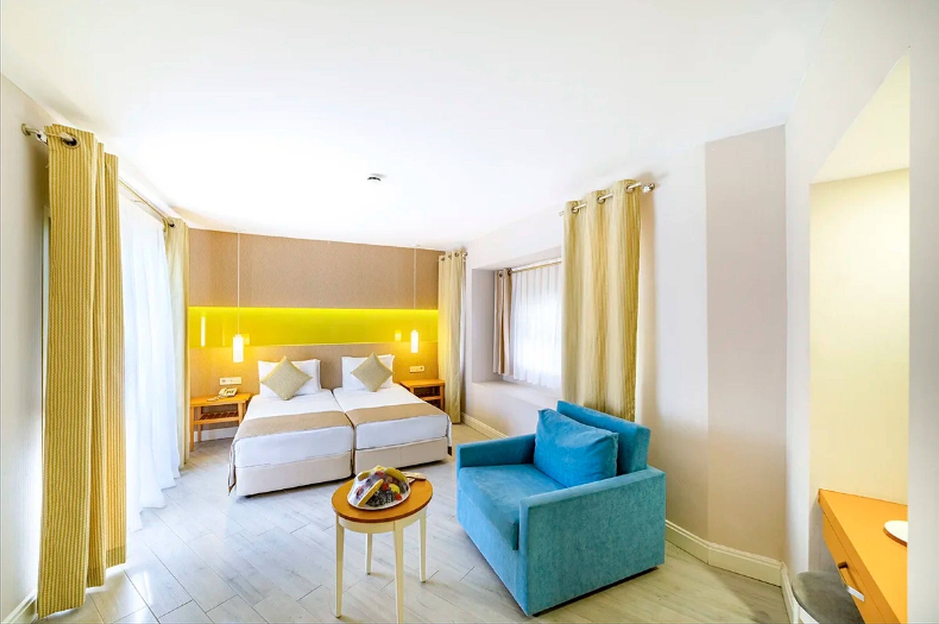 A hotel room with a bed, a blue sofa, a small table, and a nightstand.