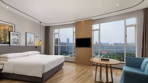 A modern hotel room with a large bed, a TV, a small table, and a city view. - Ramada by Wyndham Changsha Financial Center (Changsha)