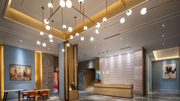 A modern hotel lobby with a reception desk, seating area, and a staircase. - Ramada by Wyndham Changsha Financial Center (Changsha)