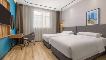 Habitación de hotel con dos camas, un escritorio, una silla, un televisor y una ventana con cortinas.