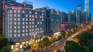 A multi-story hotel with a prominent 'RAMADA' sign, surrounded by high-rise buildings and a well-lit street. - Ramada by Wyndham Changsha Financial Center (Changsha)