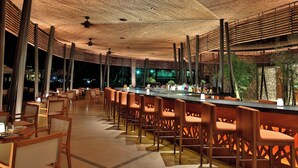 Ein Restaurant mit einer langen Bar, Holzstühlen und einer Holzdielendecke.