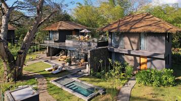 Una villa moderna con piscina, mobiliario exterior y una estructura de techo de paja.