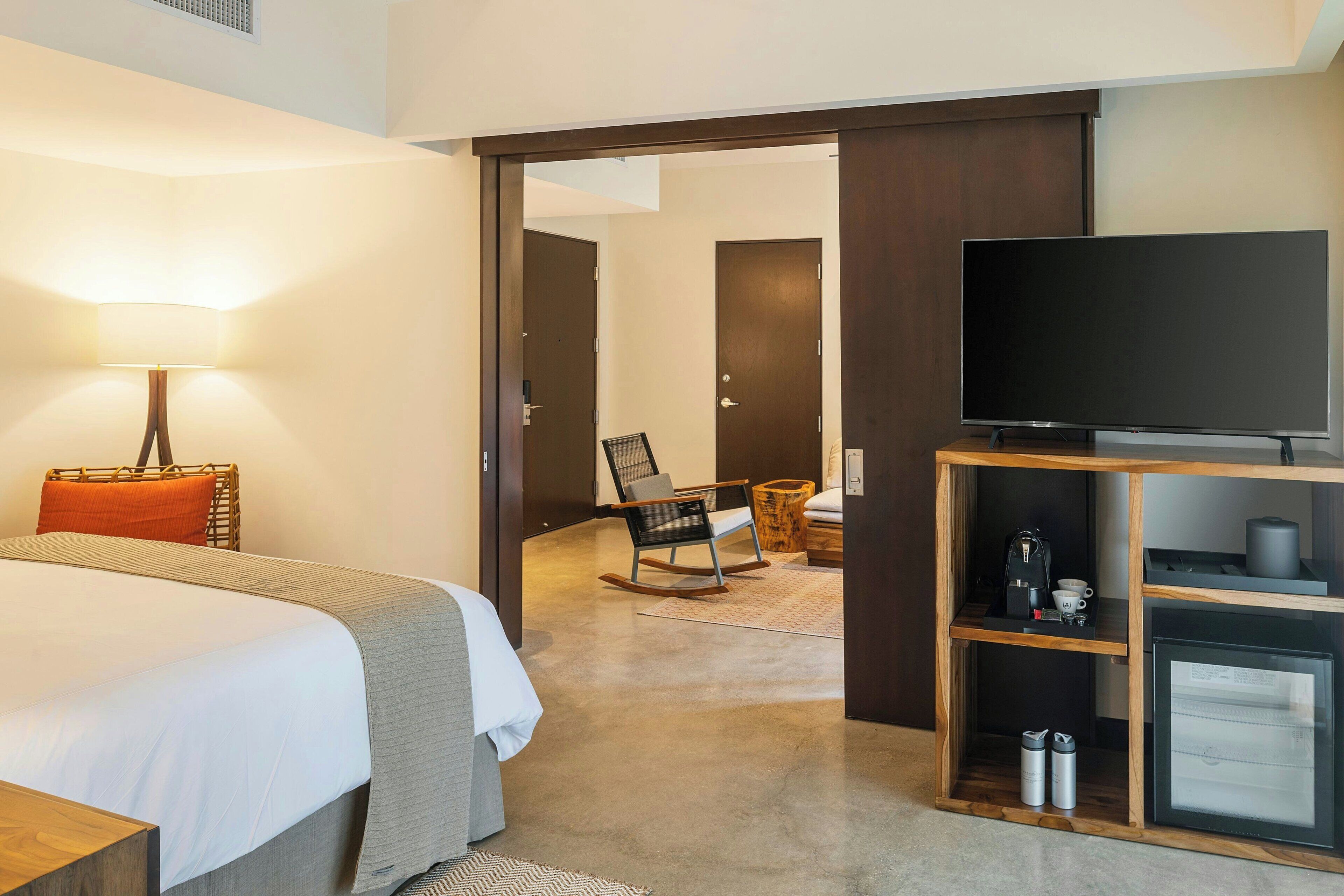 A hotel room with a bed, a TV, a coffee machine, and a small refrigerator.