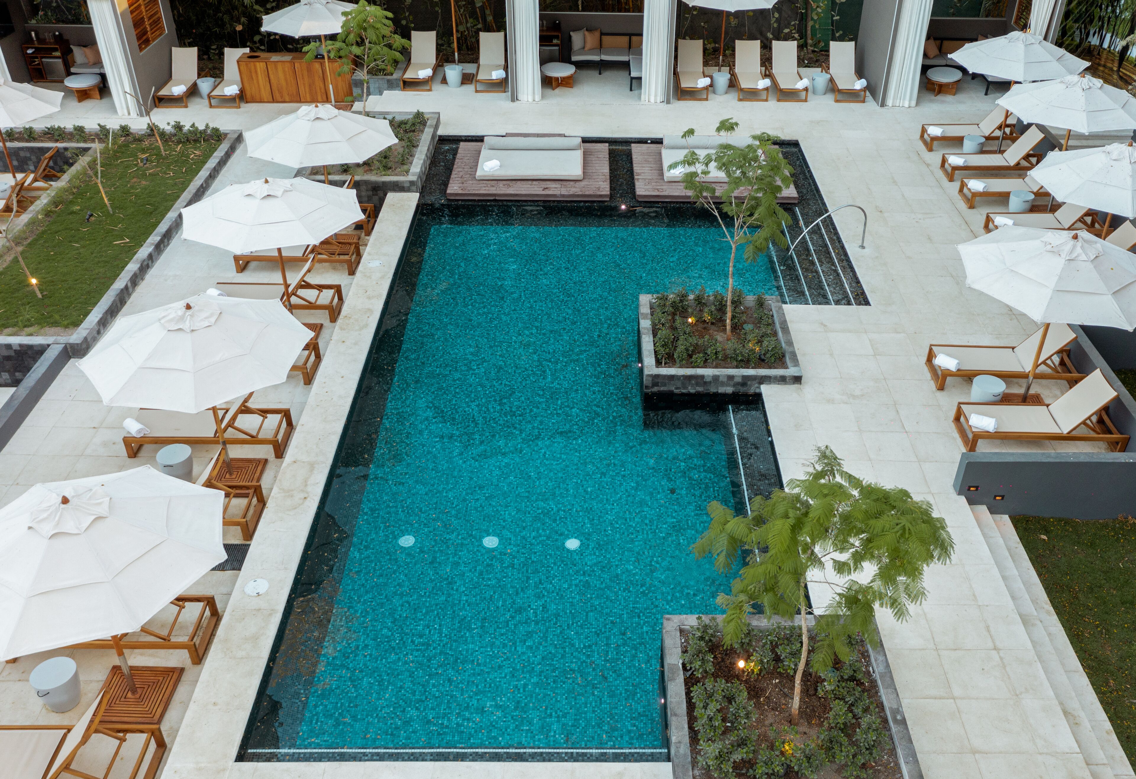 A rectangular pool with lounge chairs and umbrellas around it.