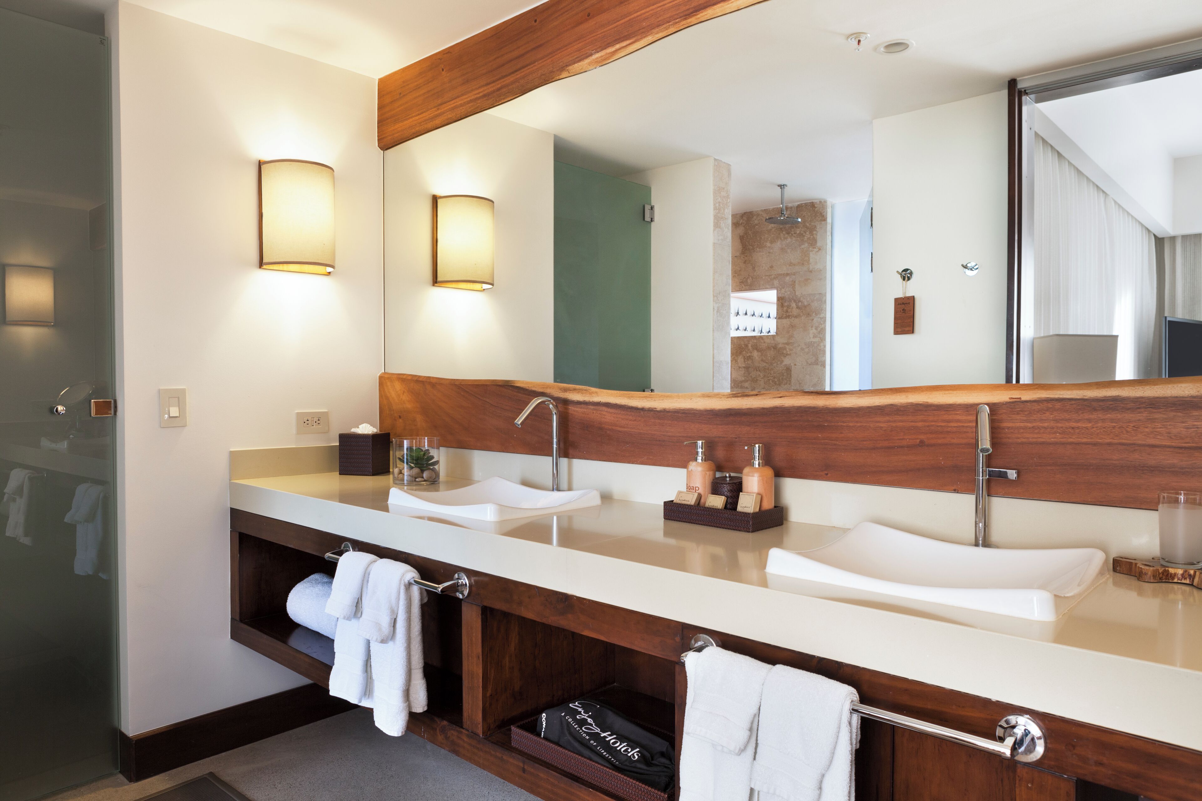 Une salle de bain moderne avec deux lavabos, un grand miroir et des meubles en bois.