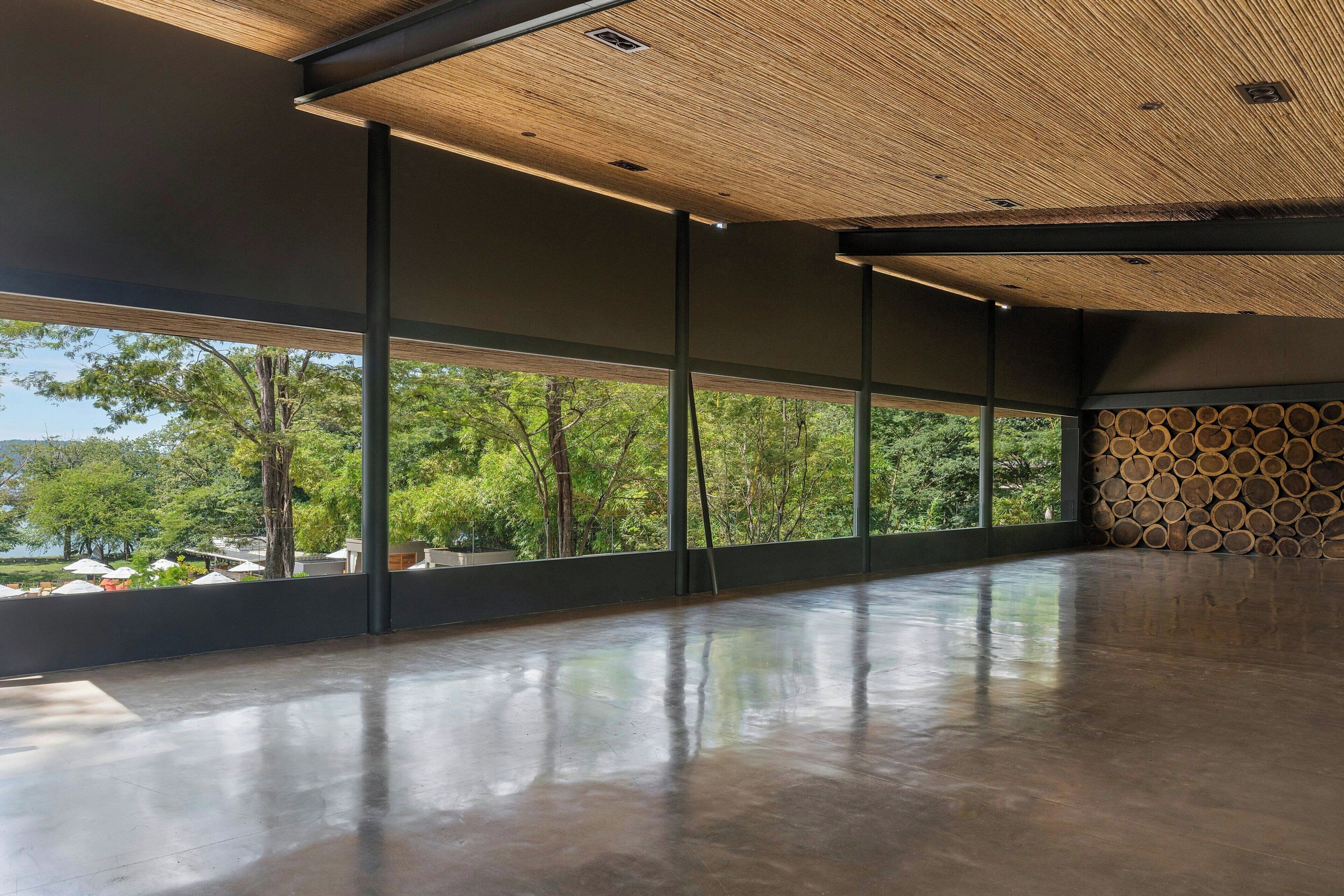 A spacious interior with large windows, a polished concrete floor, and a ceiling with a wooden texture.