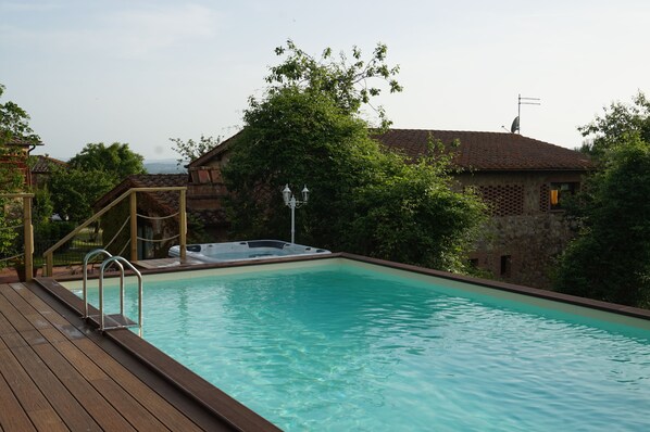 A swimming pool with a wooden deck and a hot tub.