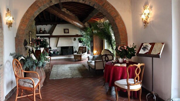 Un interior con un arco de ladrillo, muebles de madera, una chimenea y plantas decorativas.
