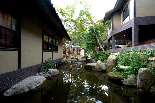Un edificio tradicional japonés con un estanque de carpas y un sendero de piedra.