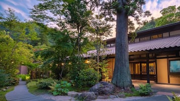 Traditional Japanese-style building surrounded by lush greenery and a stone pathway.