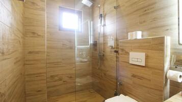 Un baño moderno con paneles de madera, cabina de ducha con mampara de vidrio, inodoro y lavamanos con espejo.