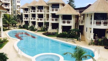 Een buitenzwembad, parasols bij het zwembad en ligstoelen