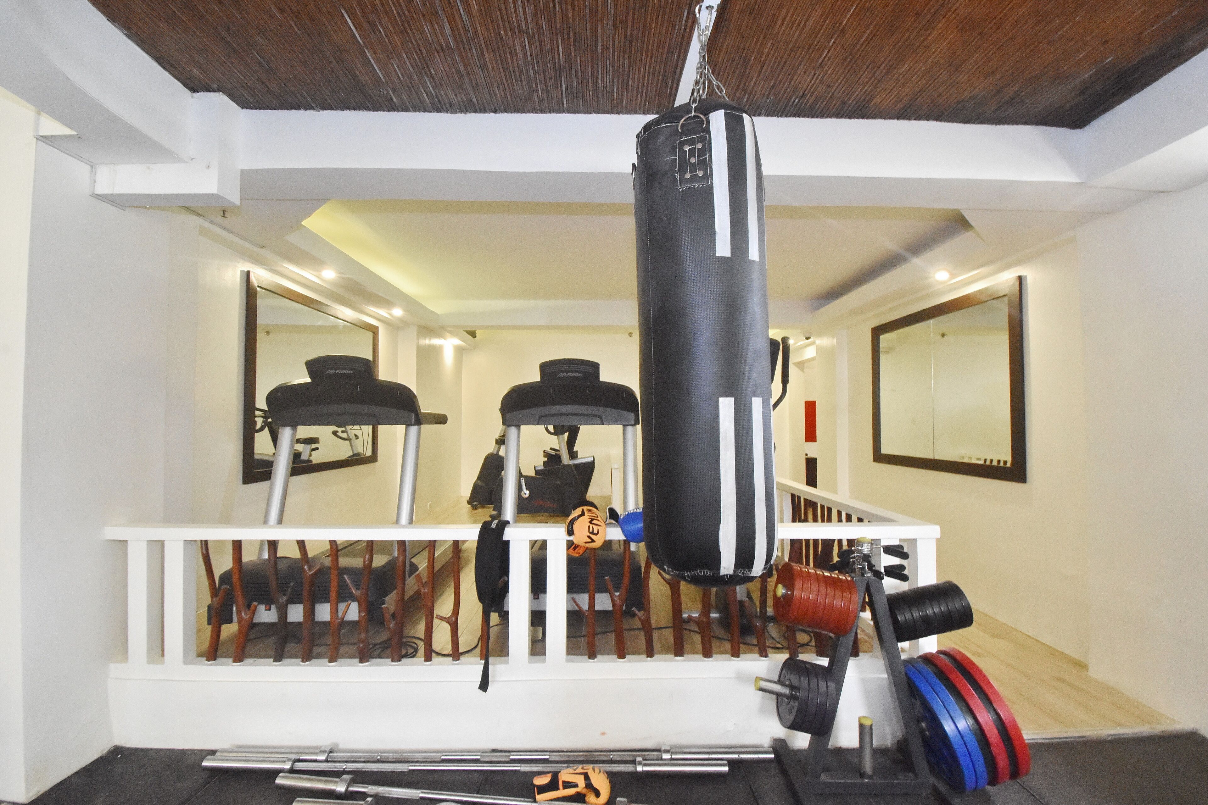 Un gimnasio en casa con un saco de boxeo, banco de pesas y diversos equipos de ejercicio.