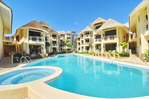 A resort with a central swimming pool, multiple balconies, and thatched-roof buildings. - Ambassador In Paradise Resort (Boracay Island)