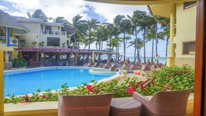A resort pool area with lounge chairs, a bar, and a view of the ocean. - Ambassador In Paradise Resort (Boracay Island)