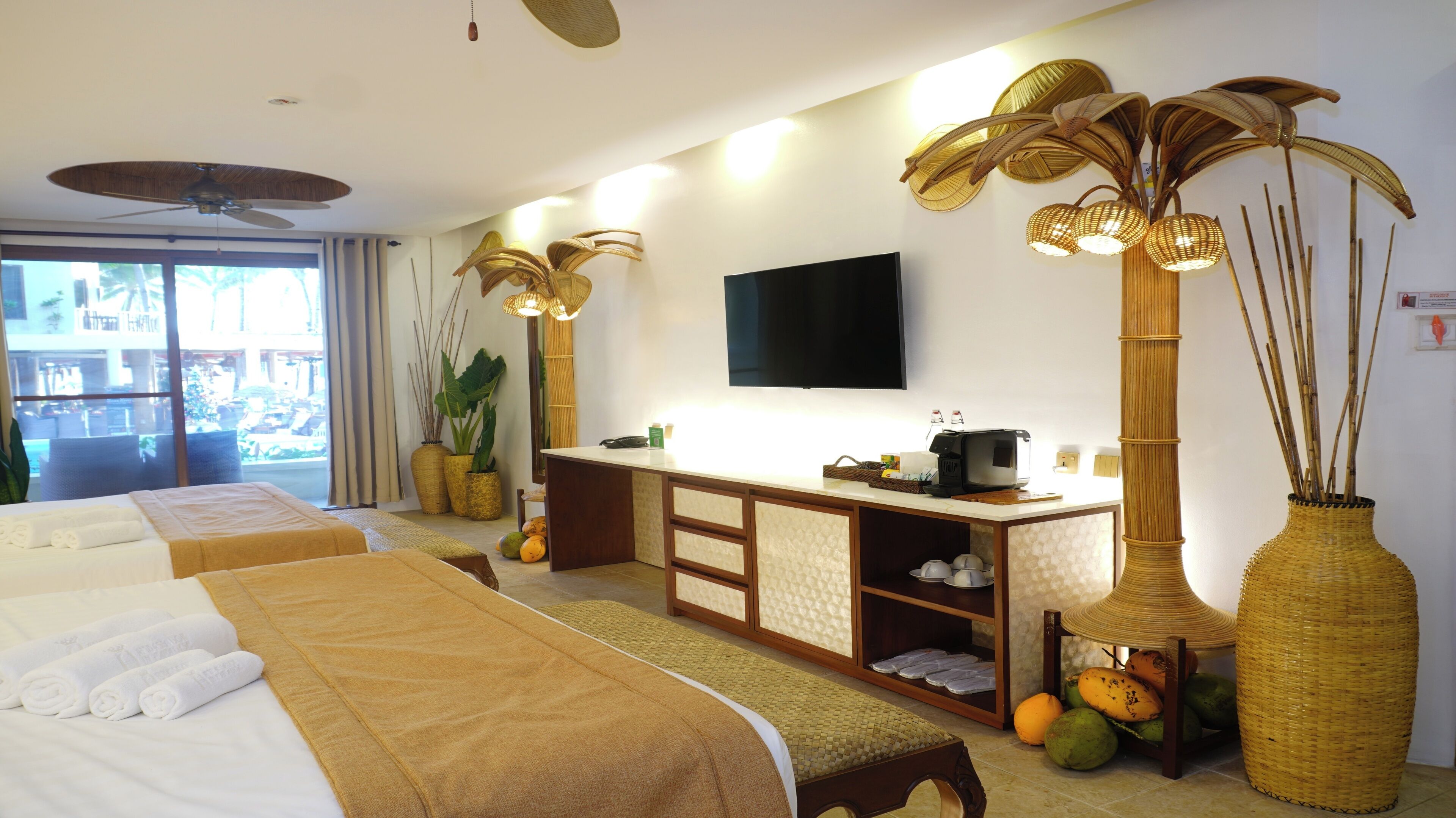 A hotel room with two beds, a TV, a minibar, and a large window.