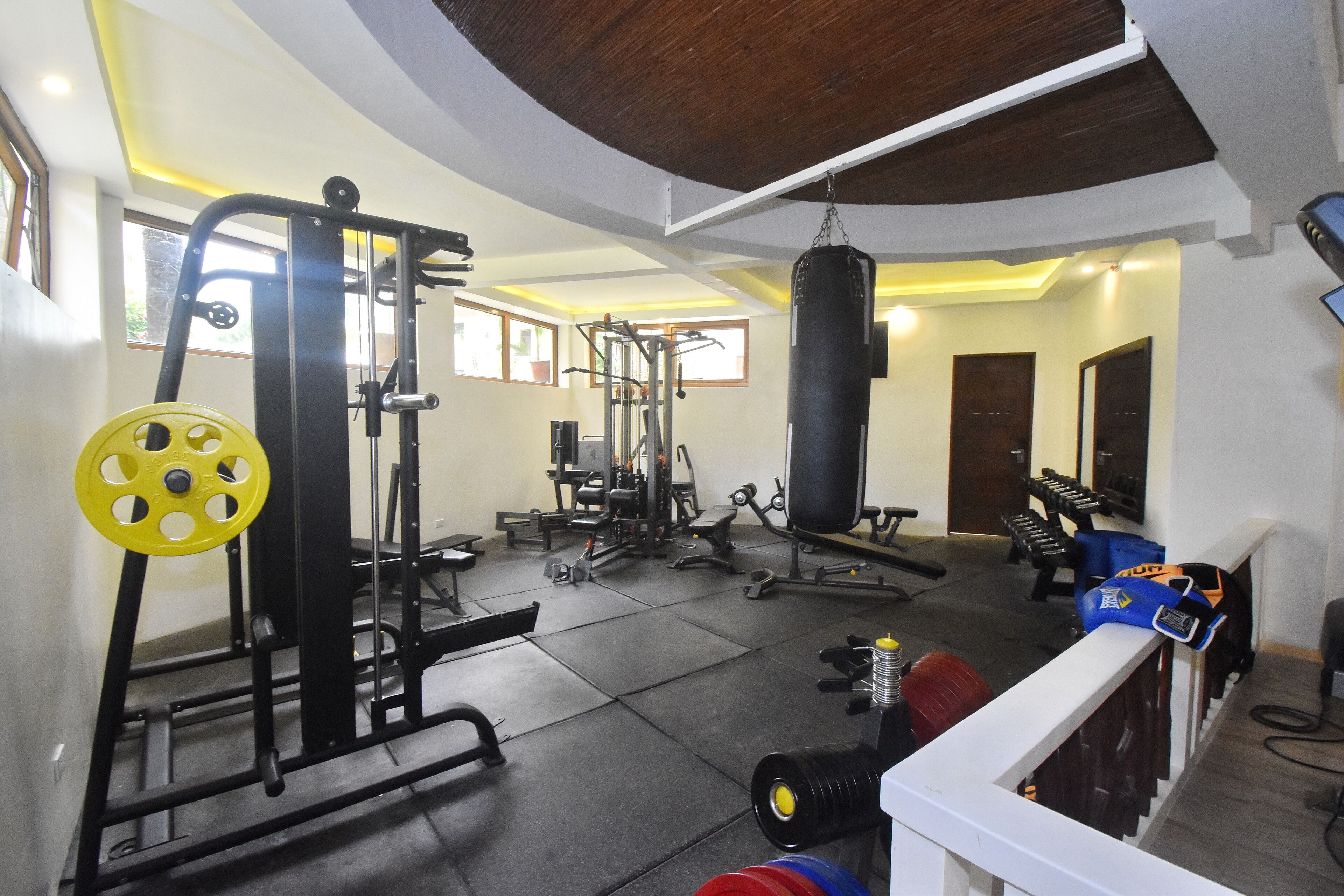 A gym with various exercise equipment, including a squat rack, weight bench, and punching bag.