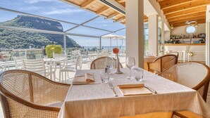 Un comedor con una mesa dispuesta para dos personas, con vistas a un paisaje montañoso.