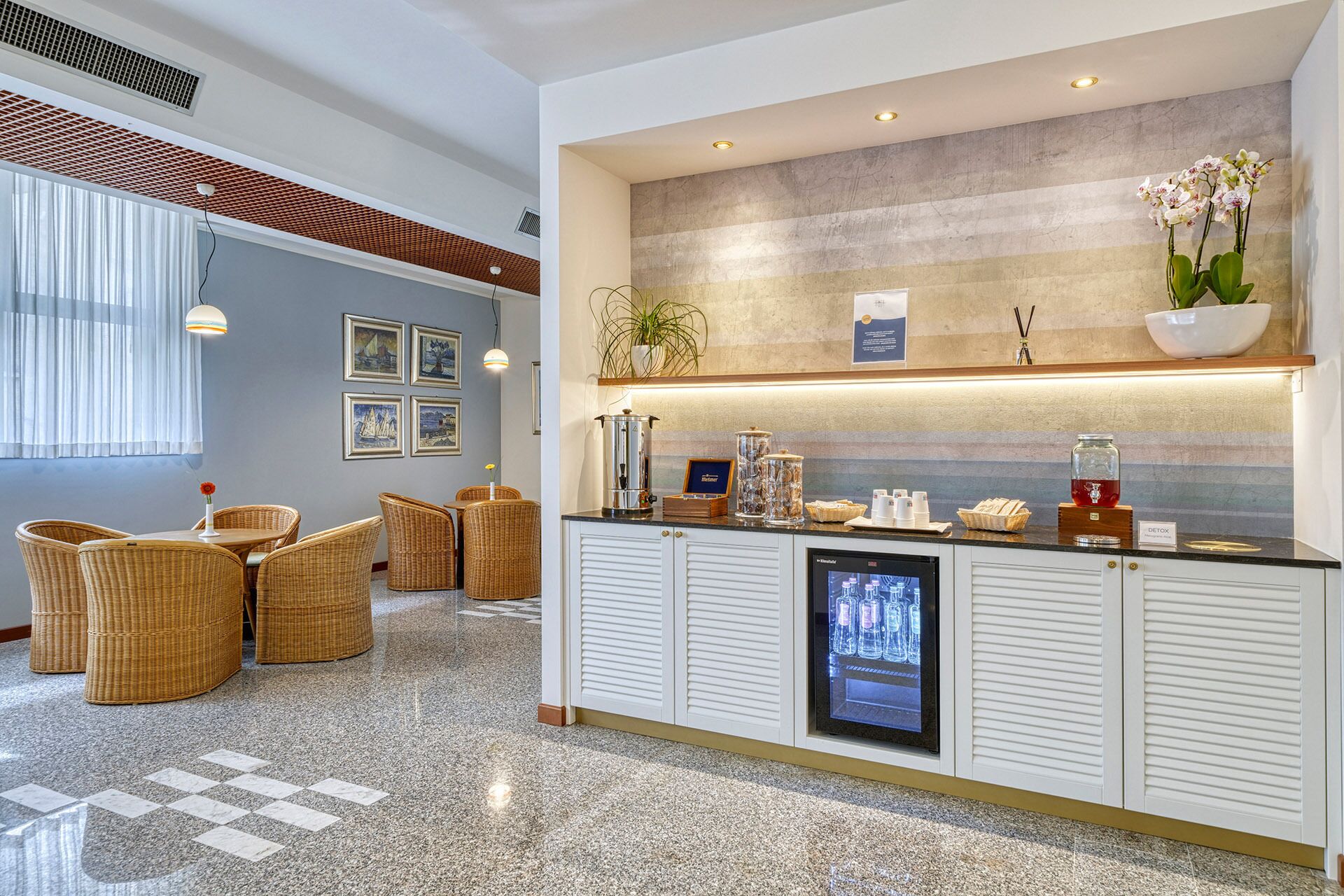 A hotel reception area with a counter, seating area, and a television screen.