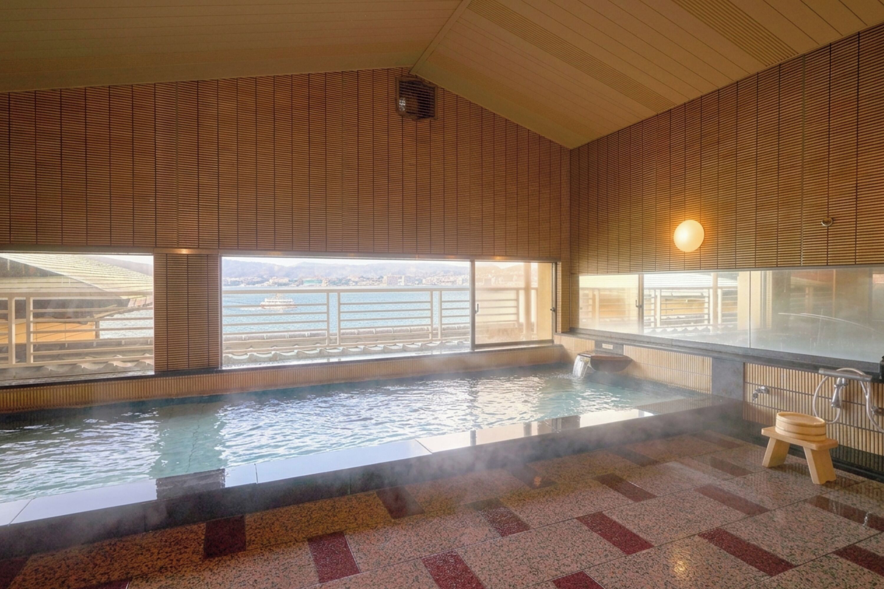 A hot spring bath with a view of a bridge and cityscape.