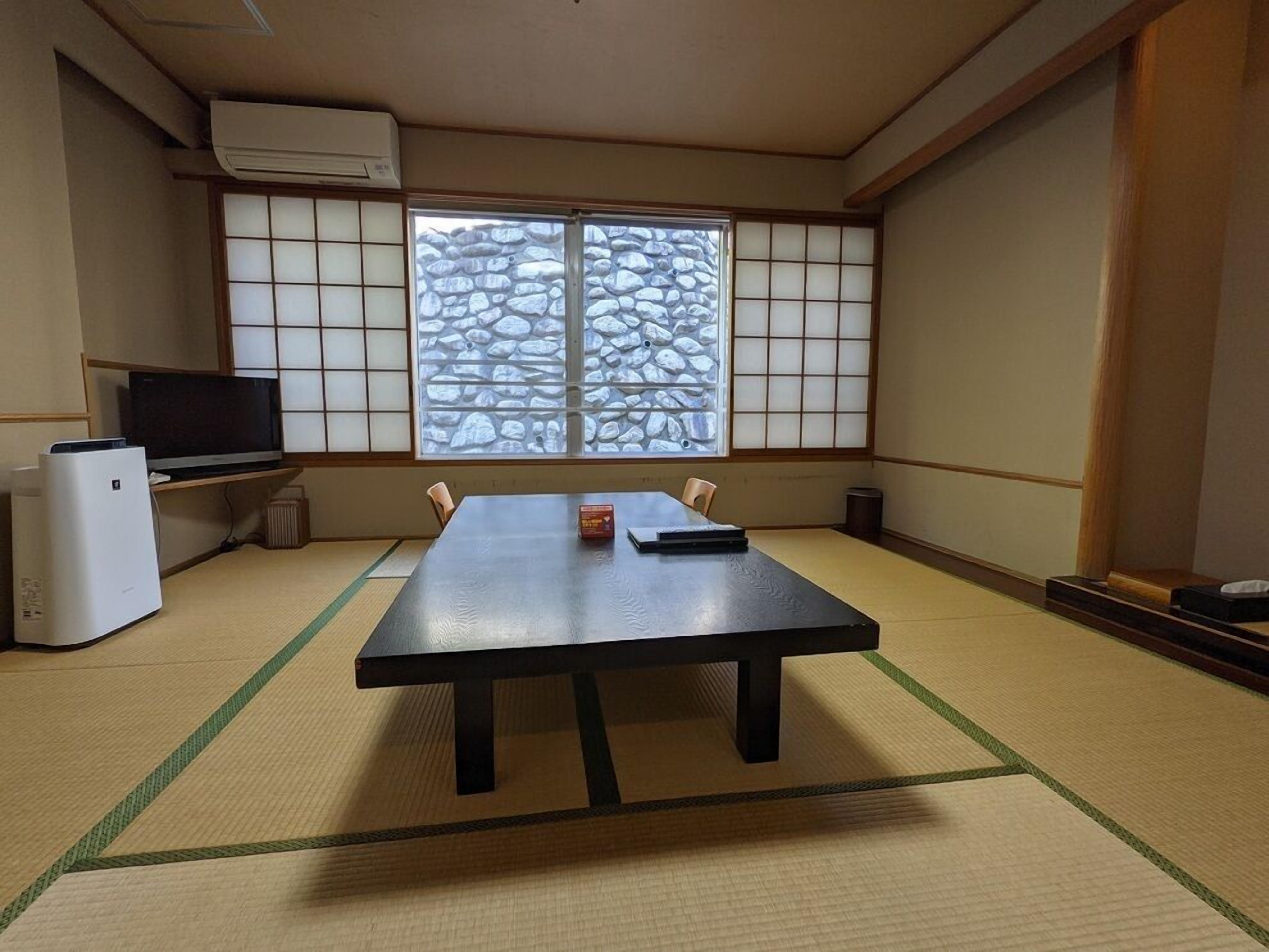 Une pièce avec un sol recouvert de tatamis, comprenant une table basse en tatami, un téléviseur et un réfrigérateur.