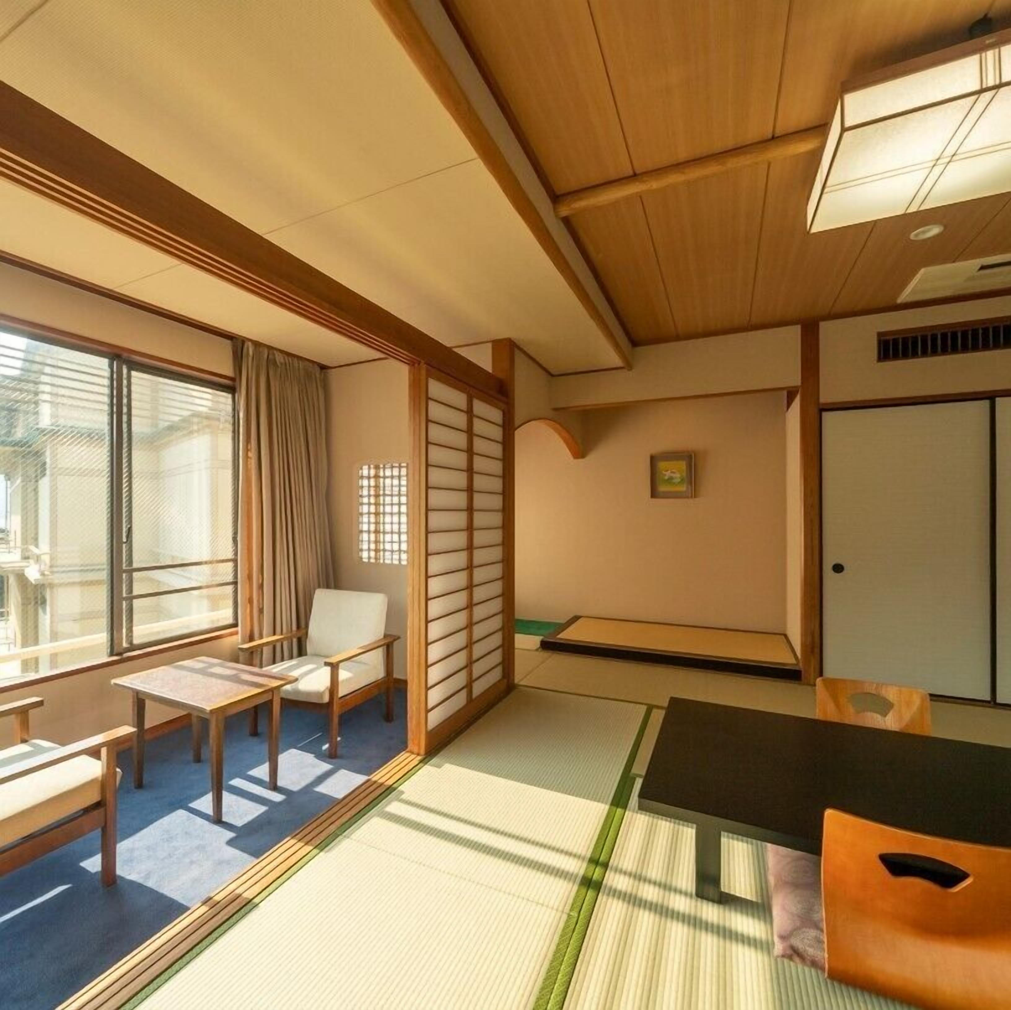 Une pièce de style japonais traditionnel, avec un sol recouvert de tatamis, une table basse, une chaise et des portes coulissantes.