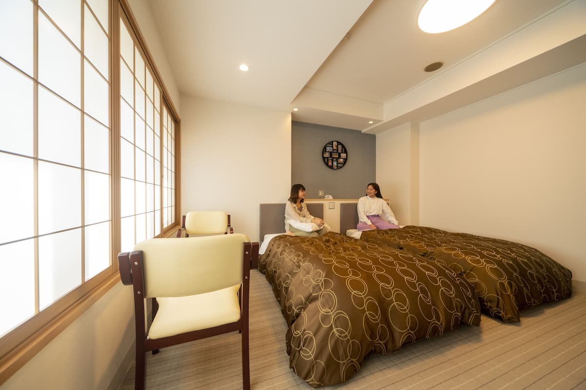 A hotel room with a large bed, a chair, and a wall-mounted artwork.