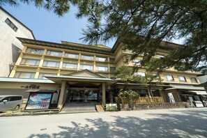 A multi-story hotel with a traditional architectural design, featuring a prominent entrance with steps and a covered area. - Hotel Miyarikyu (Hatsukaichi)