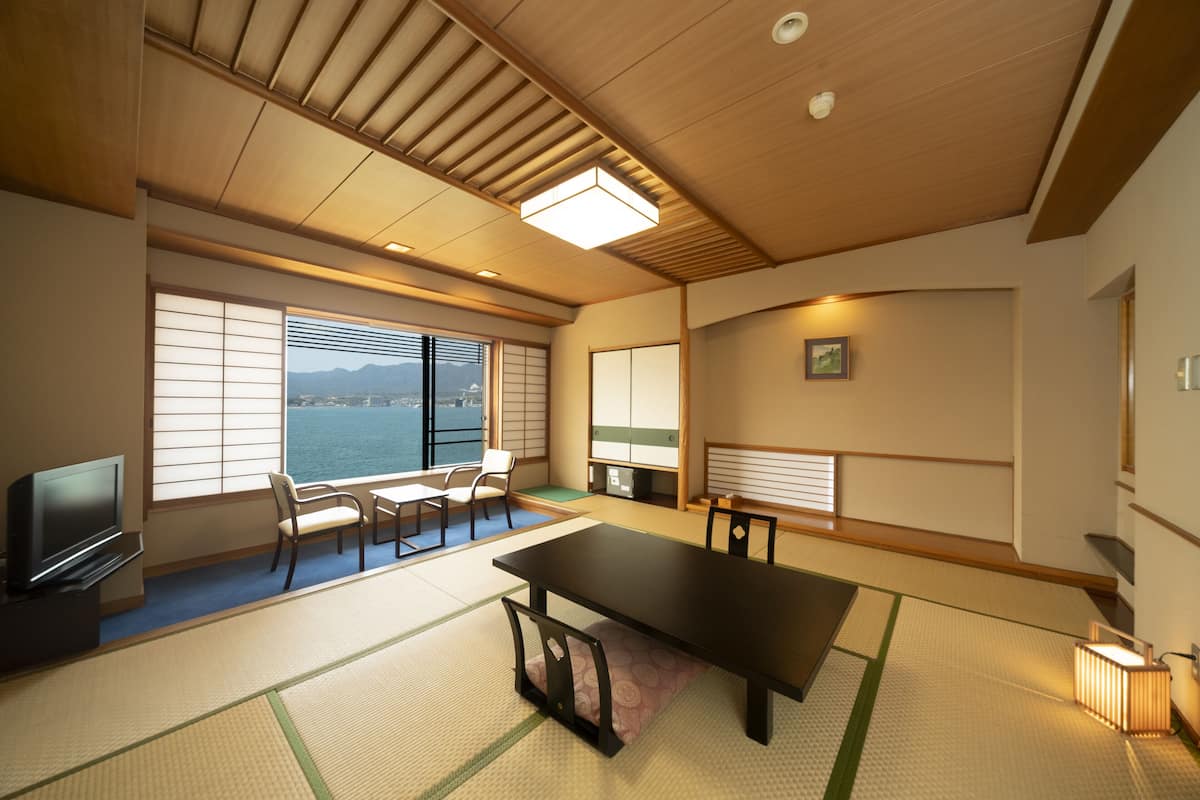 A traditional Japanese room with tatami flooring, a low table, and sliding doors.
