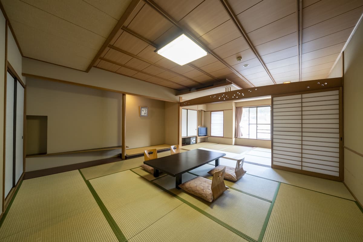 A traditional Japanese room with tatami flooring, a low table, and sliding doors.