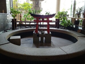 A traditional Japanese torii gate in a courtyard with a stone lantern and potted plants.