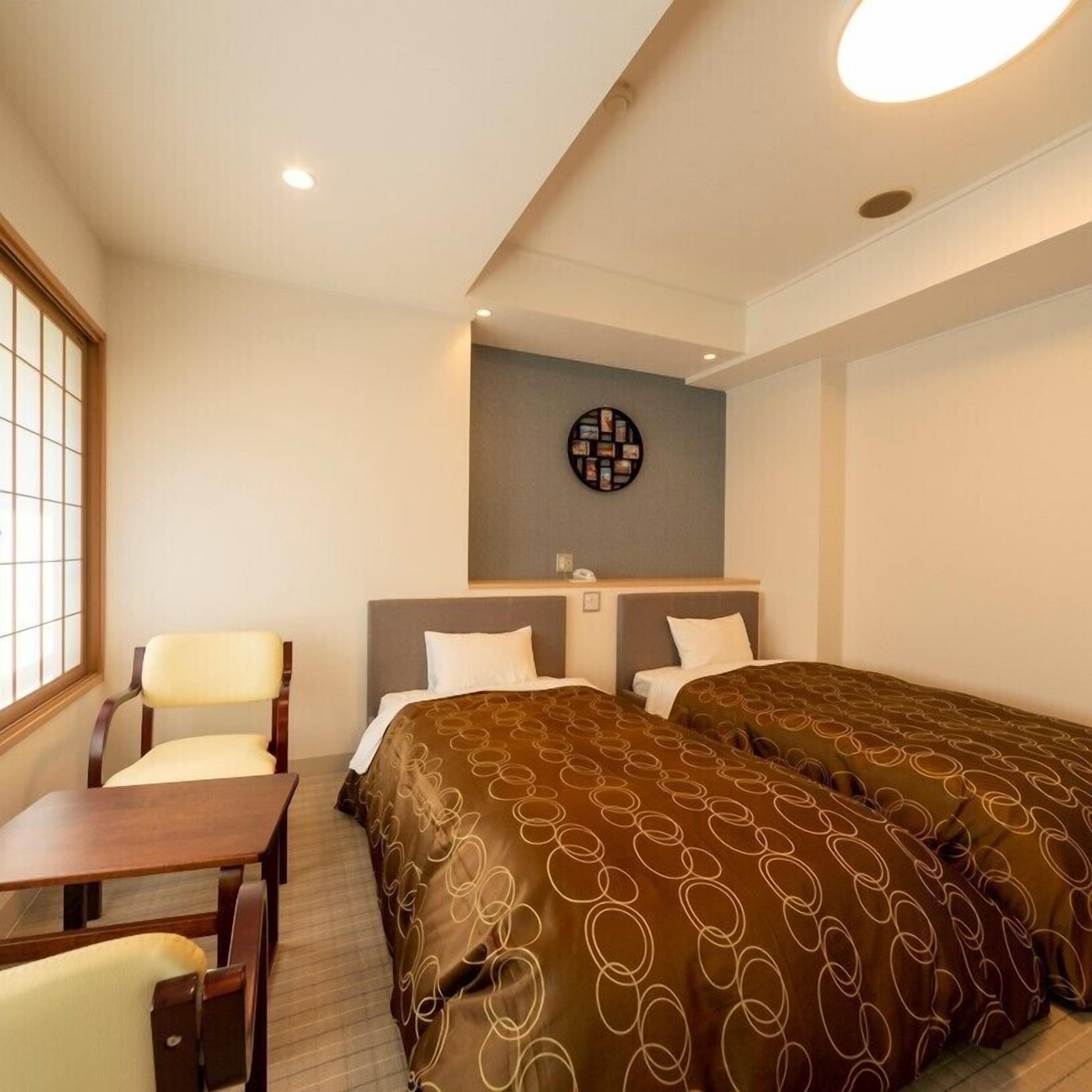 Une chambre d’hôtel avec deux lits, un bureau, une chaise et une œuvre d’art accrochée au mur.